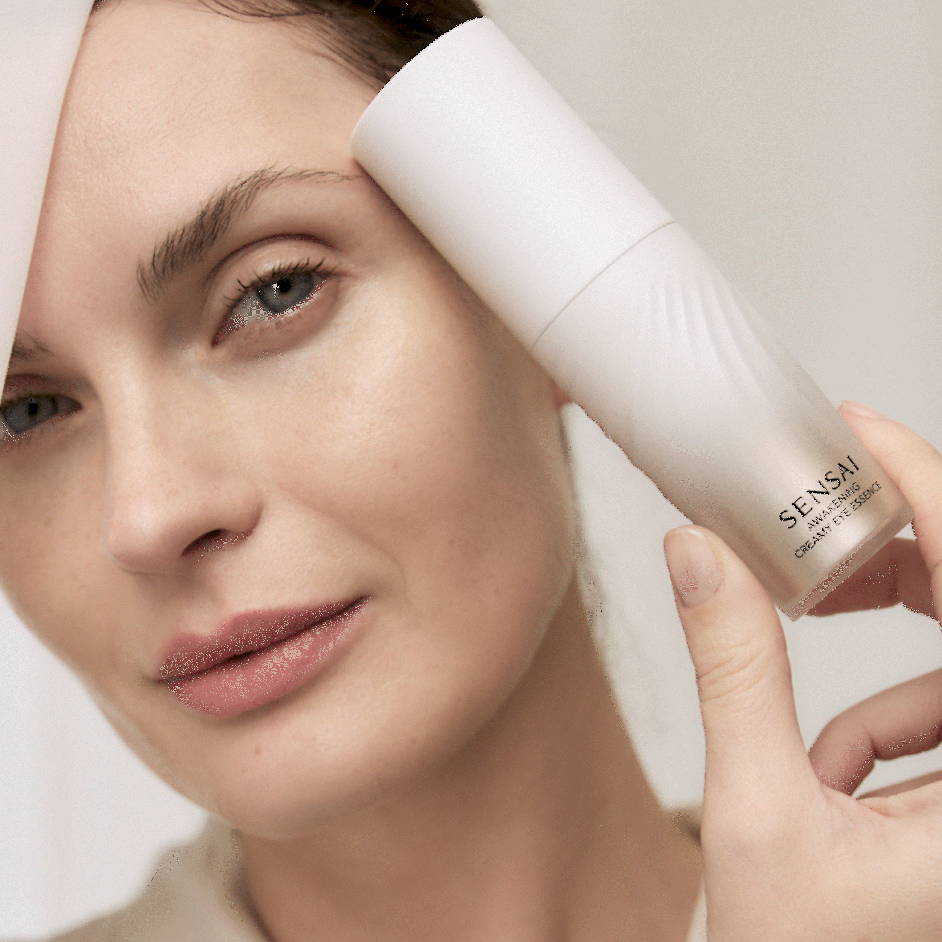 Flakon der Awakening Creamy Eye Essence wird gehalten und das Produkt wird vom Model aufgetragen 